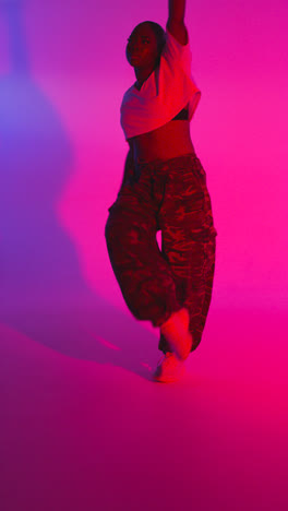 Vertical-Video-Studio-Shot-Of-Young-Woman-Dancer-Dancing-Against-Blue-And-Pink-Lit-Background-2